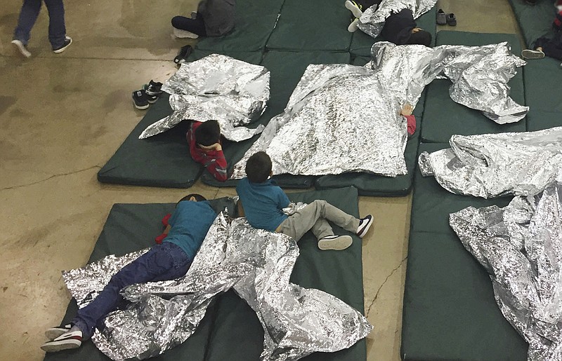 FILE - In this Sunday, June 17, 2018, file photo provided by U.S. Customs and Border Protection, people who've been taken into custody related to cases of illegal entry into the United States, rest in one of the cages at a facility in McAllen, Texas.