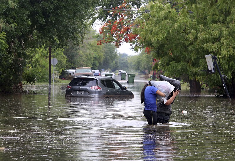 Residents carry their belongings through high water after heavy rains caused water to rise and flood whole neighborhoods on Wednesday, June 20, 2018, in Weslaco, Texas. (Joel Martinez/The Monitor via AP)

