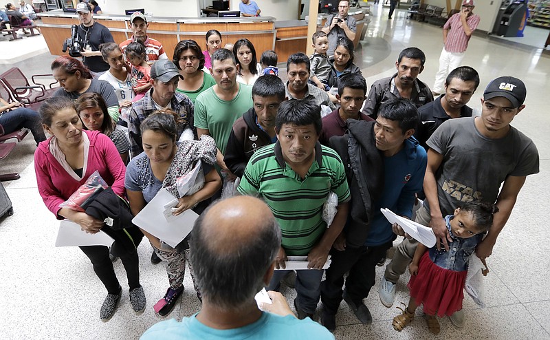 Immigrants listen to instructions from a volunteer inside the bus station after they were processed and released by U.S. Customs and Border Protection, Friday, June 22, 2018, in McAllen, Texas. (AP Photo/David J. Phillip)