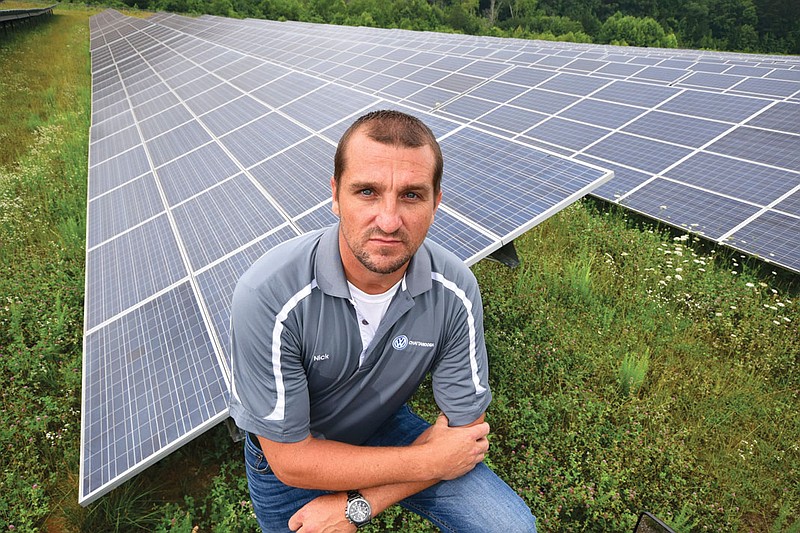 Nick Tuders, advanced electric specialist for Volkswagen, stands in front of a portion of the 65-acre solar farm at Volkswagen.
