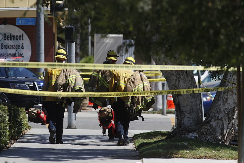 Long Beach firefighters walk along a street near a retirement home where at least one firefighter was killed in Long Beach, Calif., on Monday, June 25, 2018.