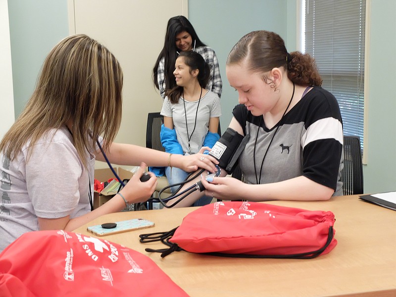 On the campus of Hamilton Medical Center in Dalton, Jenna Early, near left, checks the blood pressure of Ladashja Roberts at Med Camp, a Dalton Public Schools, Mercer University School of Medicine, Dalton State College and Hamilton Medical Center sponsored event for rising 9th grade Dalton students on Wednesday. In back, Nadia Fajardo, top, listens to the lungs of Celina Mendez.