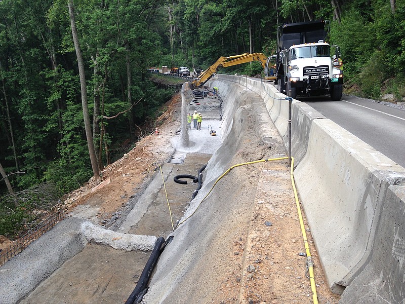 A dump truck and track hoe deliver a load of gravel to the work site on State Route 68 in Rhea County where repairs are under way to slide damage that wiped out one lane of the road. The remaining lane must be used by both travelers and work crews who must shut down the lane for some materials deliveries.