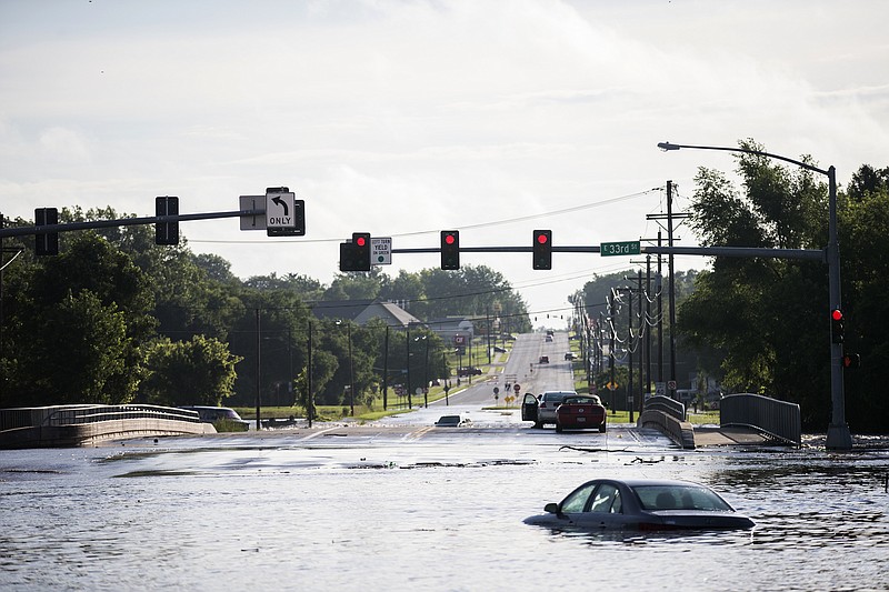 
              Two men sit stranded in their cars, surrounded by flood water from Fourmile Creek on the bridge at the intersection of Hubbell Avenue and East 33rd Street on Des Moines' east side on Sunday morning, July 1, 2018 after heavy rain fell overnight. The creek crested at a record 17.47 feet around 6:00 a.m. (Kelsey Kremer/The Des Moines Register via AP)
            