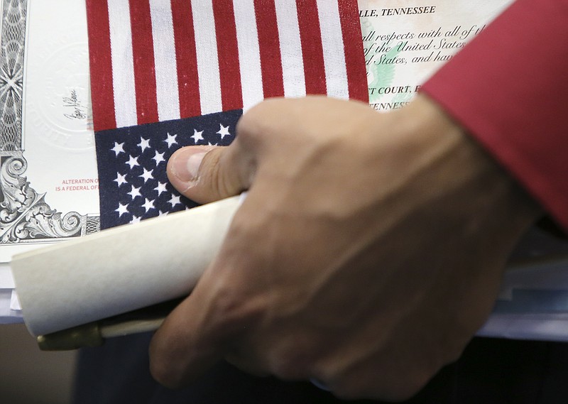 Staff file photo by C.B. Schmelter / Holding an American flag and his new naturalization certificate, Honduran-born American Bryan Aleman waits to have his picture taken after a Naturalization Ceremony in Susan Ingram Thurman Gymnasium at Red Bank High School last September in Chattanooga, Tenn. About 50 people took the Oath of Allegiance to become American citizens during the ceremony. It was one of many ceremonies being held across the county for Constitution Day and Citizenship Day.