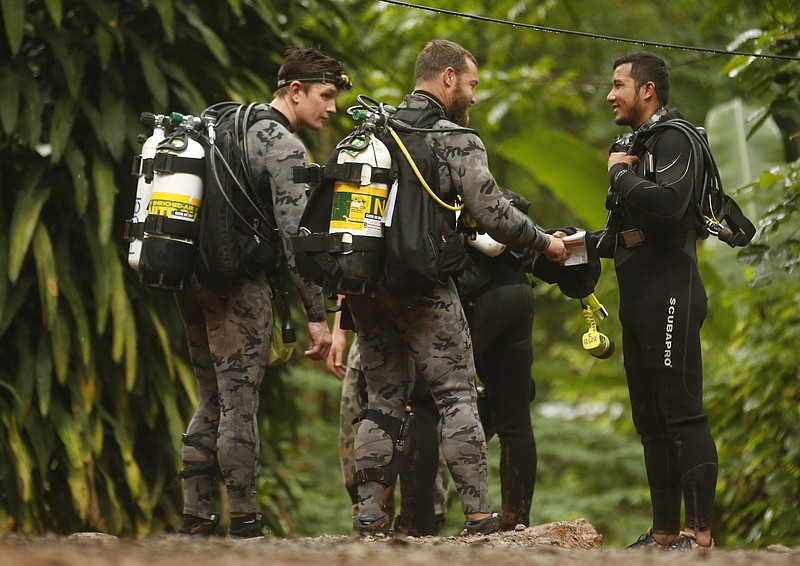 Australian Federal Police and Defense Force personnel talk to a Thai rescuer, right, before diving after the 12 boys and their soccer coach were found alive, in Mae Sai, Chiang Rai province, in northern Thailand, Tuesday, July 3, 2018. The 12 boys and soccer coach found after 10 days are mostly in stable medical condition and have received high-protein liquid food, officials said Tuesday, though it is not known when they will be able to go home. (AP Photo/Sakchai Lalit)
