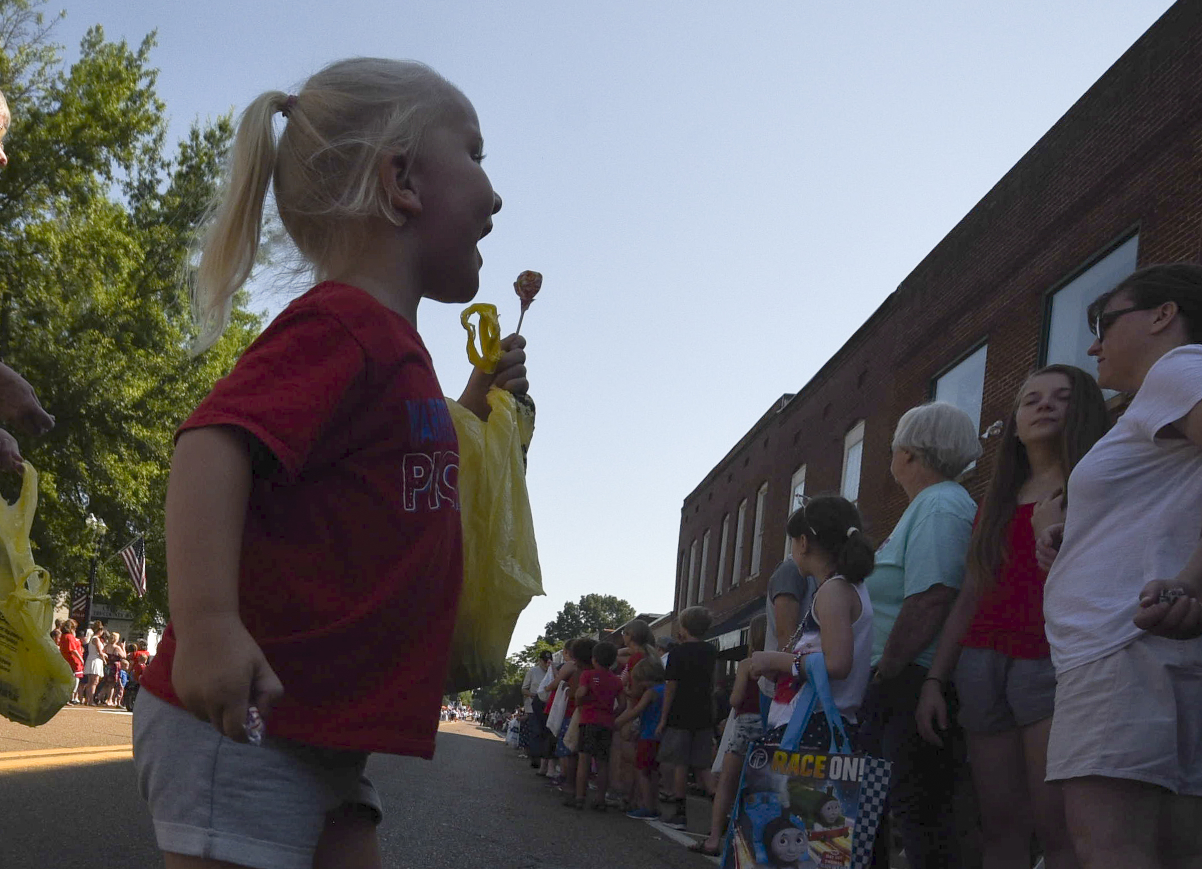 Sadie Clark, 3, hurries back into the shade after grabbing a piece of candy thrown from vehicles on Rankin Avenue  in the annual Fourth of July parade in downtown Dunlap.