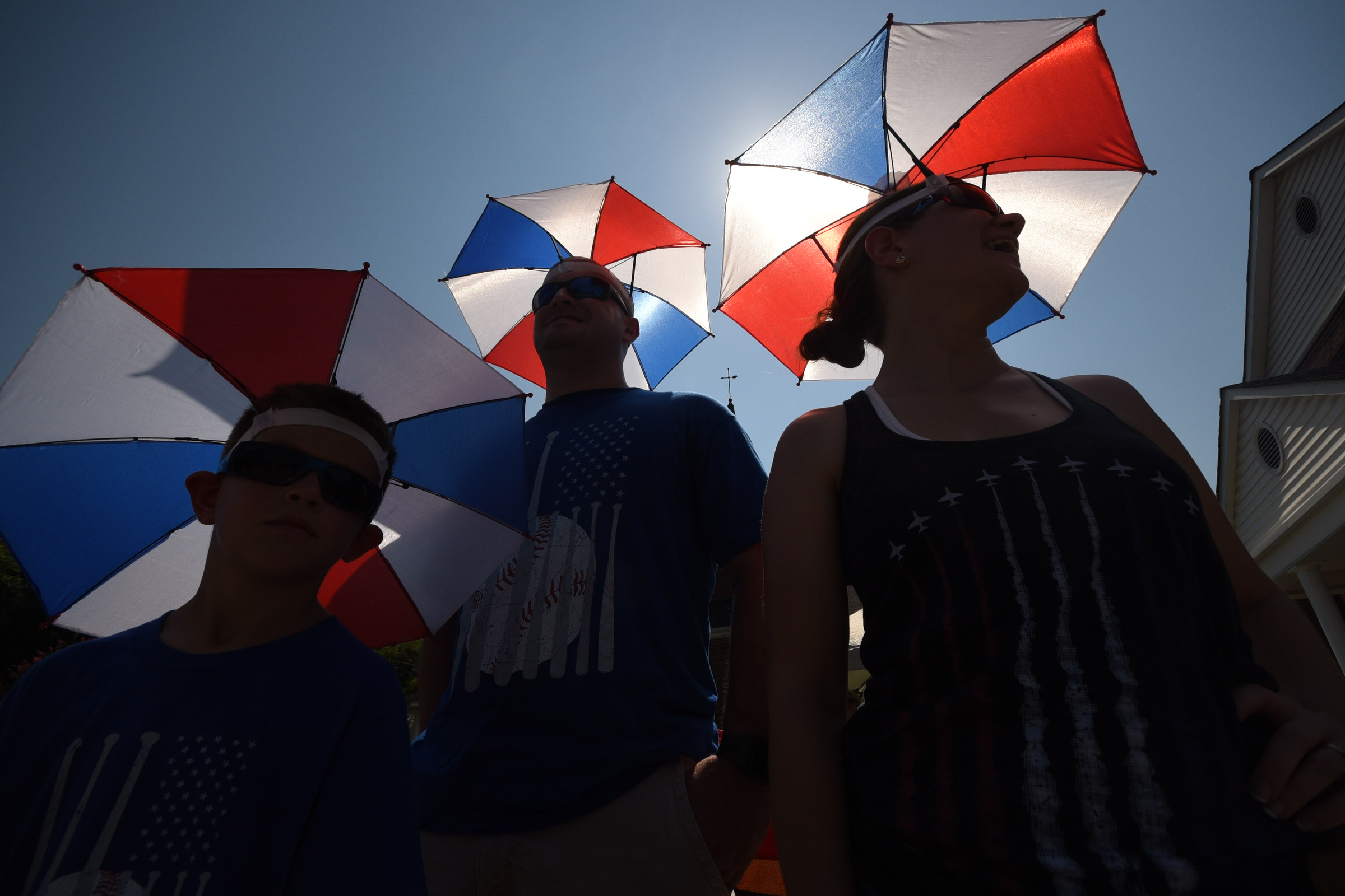 Luke, Zach and Amy Smith, of Chattanooga, watch the annual Fourth of July parade with shade from their umbrella hats Wednesday in downtown Dunlap.
