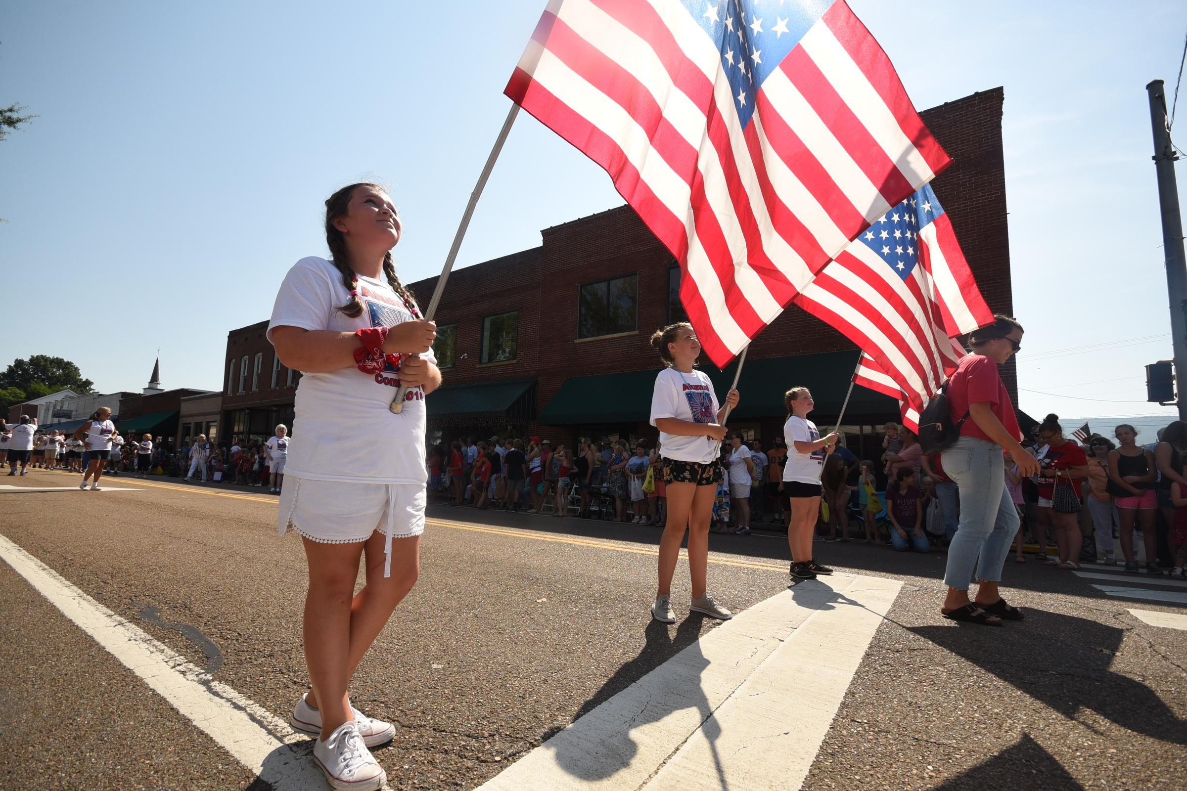 Grey Kelley, left, checks the flight of her American flag before marching on in the annual Fourth of July parade. Hannah Kurley stands next to her.