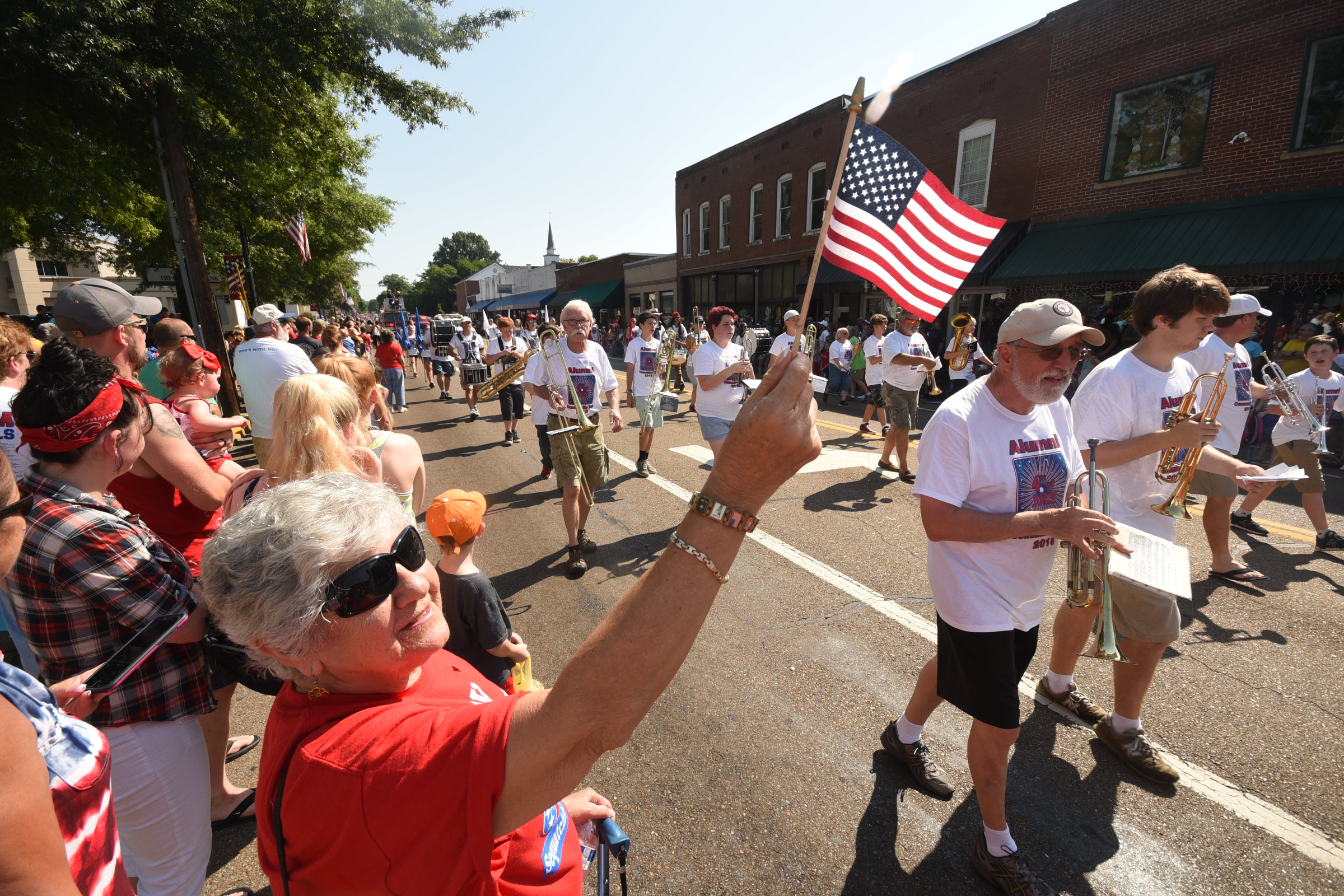 New Sequatchie County resident Donna Howard flies her flag as the Sequatchie County Alumni Band passes on Rankin Avenue Wednesday morning in the annual Fourth of July in downtown Dunlap.