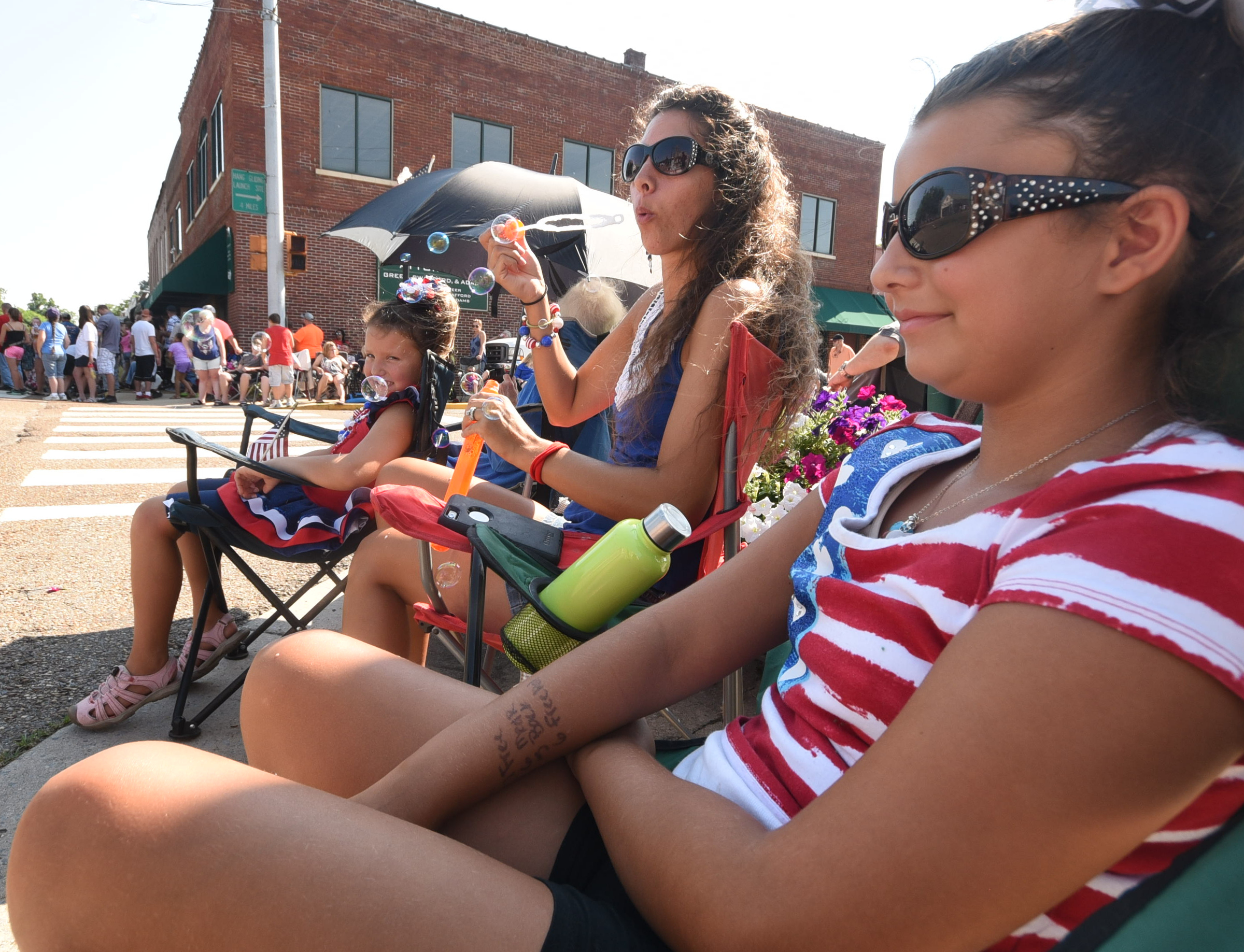 Bubbles fly from Teresa Shank, center, as her daughters  Carolina, right, and Lillian watch the annual Fourth of July parade Wednesday in downtown Dunlap.