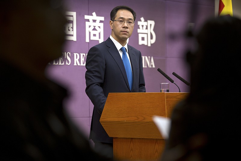 In this March 29, 2018, photo, Chinese Ministry of Commerce spokesman Gao Feng listens to a reporter's question during a press conference at the Ministry of Commerce in Beijing. A Chinese government spokesman has said Thursday, July 5, 2018, that Beijing "will not bow in the face of threats and blackmail" on the eve of U.S. tariff hikes and will defend its interests. (AP Photo/Mark Schiefelbein)