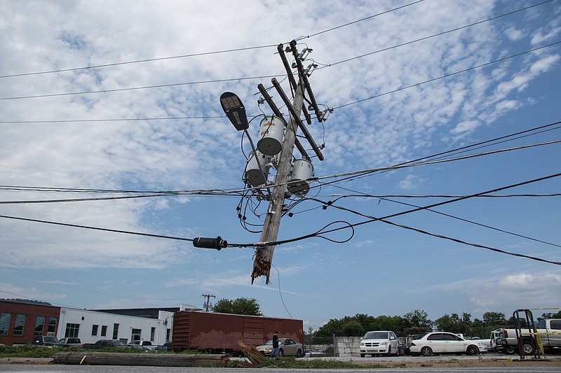 A utility pole is suspended by utility wires after a red pickup truck left the road and snapped the pole at its base in the 1800 block of Central Avenue on Thursday, July 5, 2018, in Chattanooga, Tenn. There were no injuries in the crash, but Central Avenue was closed to traffic to repair the damage to the pole and power lines.