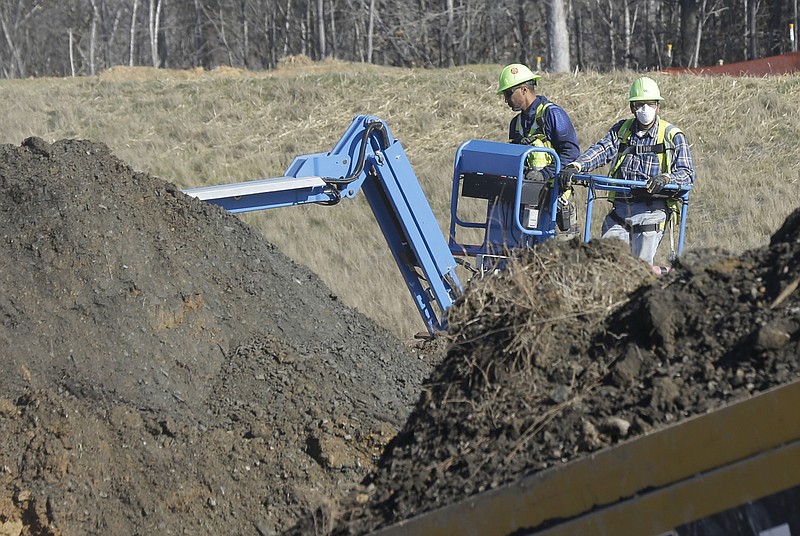FILE - In this Jan. 14, 2016 file photo, workers excavate coal ash-laden soil to be removed from the Dan River Steam Station in Eden, N.C.  A string of decisions by North Carolina regulators means electricity consumers could be seeing a $5 billion bill to clean up mountains of waste Duke Energy created by spending decades burning coal to produce power.  State utilities regulators late last June 2018 decided that both North Carolina divisions of the country’s No. 2 power company could charge ratepayers for the cleanup.  (AP Photo/Gerry Broome, File)