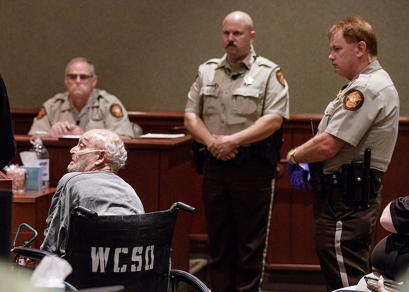 Whitfield County Sheriff's deputies stand near Jay Thomas Burlison as he uses oxygen from a wheelchair during his bond hearing in Whitfield County Superior Court on Friday, July 6, 2018, in Dalton, Ga. Judge Scott Minter denied bond for Burlison, who earlier this week was arrested in Lawrenceburg, Tenn., for a 1984 murder at a Rocky Face gas station after more than 30 years on the run.