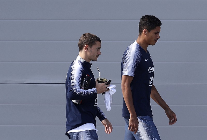 
              FILE - In this Monday, July 2, 2018 file photo France's Antoine Griezmann, left, holding a mate gourd, and Raphael Varane arrive at a training session at the 2018 soccer World Cup in Glebovets, Russia. France forward Antoine Griezmann has arrived for the World Cup match against Uruguay sipping from a mate gourd _ perhaps as a silent retort to Luis Suarez. The Uruguay striker took a verbal shot at Griezmann earlier this week ahead of Friday's quarterfinal, accusing him of trying to be Uruguayan. (AP Photo/David Vincent, File)
            