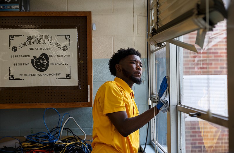 Jalen Hunt wipes down a window frame during a volunteer work day at Brainerd High School on Saturday, July 7, 2018, in Chattanooga, Tenn. Students with the University of Tennessee at Chattanooga's Bridge program as well as volunteer alumni and other community groups came out to help maintain the school's campus.