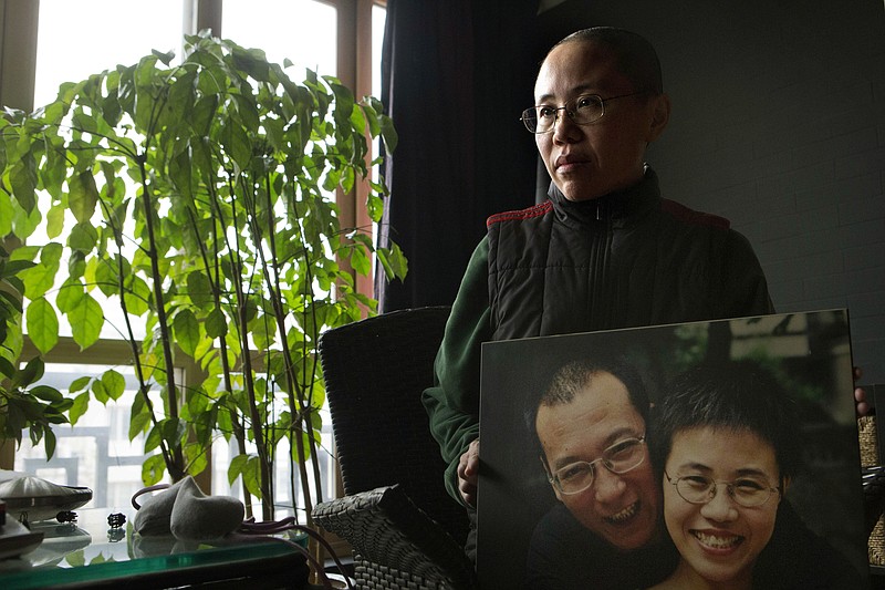 
              FILE - In this Dec. 6, 2012, file photo, Liu Xia, wife of 2010 Nobel Peace Prize winner Liu Xiaobo, poses with a photo of her and her husband during her first interview in more than two years at her home in Beijing, China. A person briefed on the matter said Tuesday, July 10, 2018, that Liu Xia, the widow of Chinese Nobel Peace Prize Laureate Liu Xiaobo, has left China for Europe after eight years under house arrest. (AP Photo/Ng Han Guan, File)
            