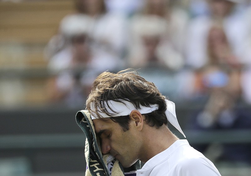 Roger Federer wipes his face after losing the fourth set of a quarterfinal with Kevin Anderson on Wednesday at Wimbledon. Federer was a point away from a straight-sets victory before Anderson put together a huge comeback.
