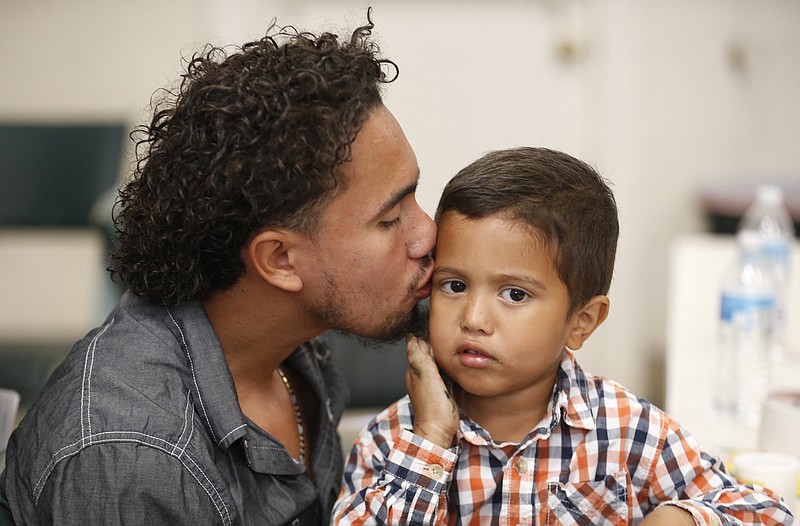 Roger Ardino 24, gives his son Roger Ardino Jr., 4, a kiss on the cheek shortly after speaking to reporters at a news conference at the Annunciation House in El Paso, Texas, Wednesday, July 11, 2018.