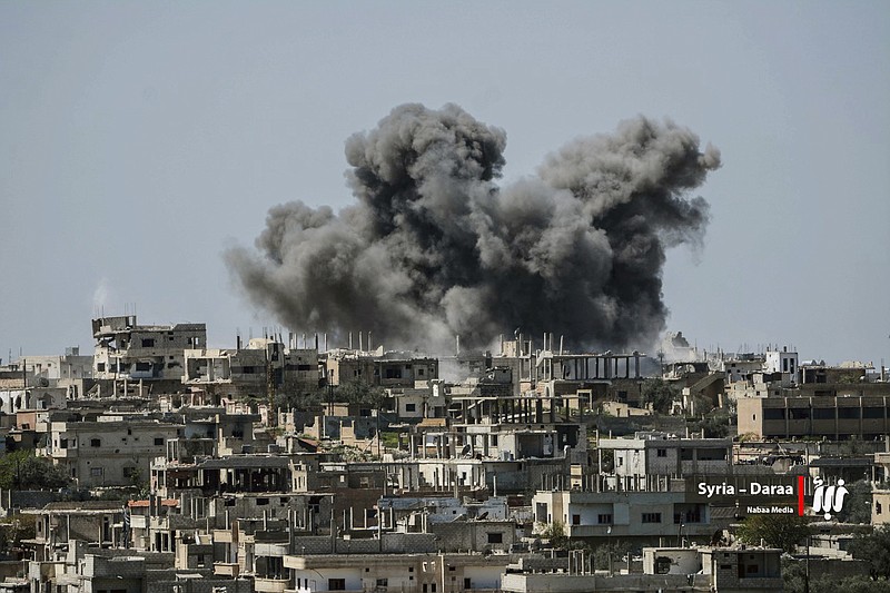 This Thursday, July 5, 2018 file photo provided by Nabaa Media, a Syrian opposition media outlet, shows smoke rising over buildings that were hit by Syrian government forces bombardment, in Daraa province, southern Syria. Syrian activists and state media said Thursday, July 12, 2018, that the rebels have agreed to surrender Daraa, the first city to revolt against President Bashar Assad with Arab Spring-inspired protests seven years ago, to government forces. (Nabaa Media via AP, File)