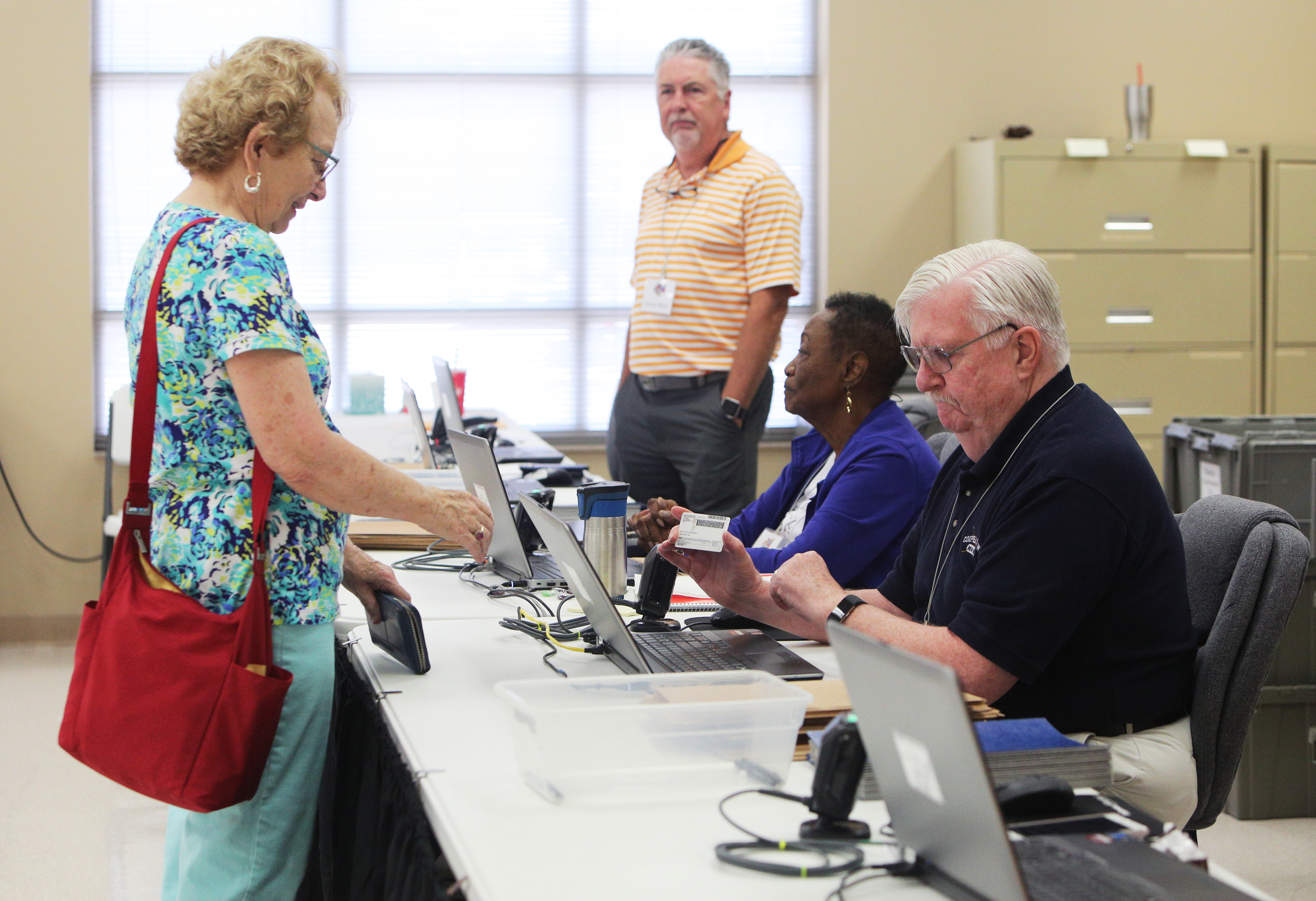 Kay Pickrell of Signal Mountain, Tennessee, gives her drivers license to Rodney Strong, an election official, as she confirms her identity and precinct before voting at the Hamilton County Election Commission Friday, July 13, 2018 in Chattanooga, Tennessee. There are four location Hamilton County residents can go for early voting, including the Hamilton County Election Commission, Brainerd Recreation Center, Collegedale City Hall Fuller Community West Room or Hixson Community Center.
