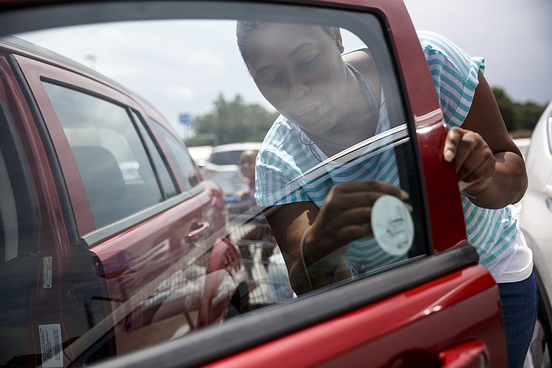Latoya Percy puts a "Look before you lock" sticker in her window after a hot car awareness news conference at the Tennessee Highway 153 Wal Mart on Aug. 2, 2016, in Chattanooga. The campaign sought to raise awareness of the dangers of leaving children and pets inside of hot cars.