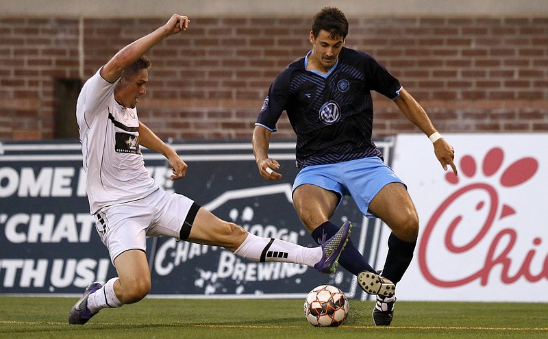 The Atlanta Silverbacks' Ryan Marcano, left, slides in to tackle Chattanooga Football Club's Juan Sanchez a uring the National Premier Soccer League Southeast Conference final on July 14, 2018, Finley Stadium. / Staff photo by C.B. Schmelter