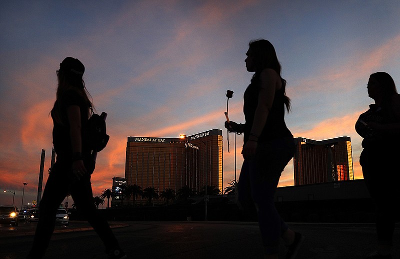 FILE - In this April 1, 2018 file photo, people carry flowers as they walk near the Mandalay Bay hotel and casino during a vigil for victims and survivors of a mass shooting in Las Vegas. 