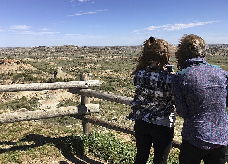 FILE--In this Wednesday, May 24, 2017, file photo, Jeanne Randall, right, and her daughter Zoe, of Shoreview, Minn., take photos at Painted Canyon in Theodore Roosevelt National Park in western North Dakota, near where a company wants to build an oil refinery about 3 miles from the park.