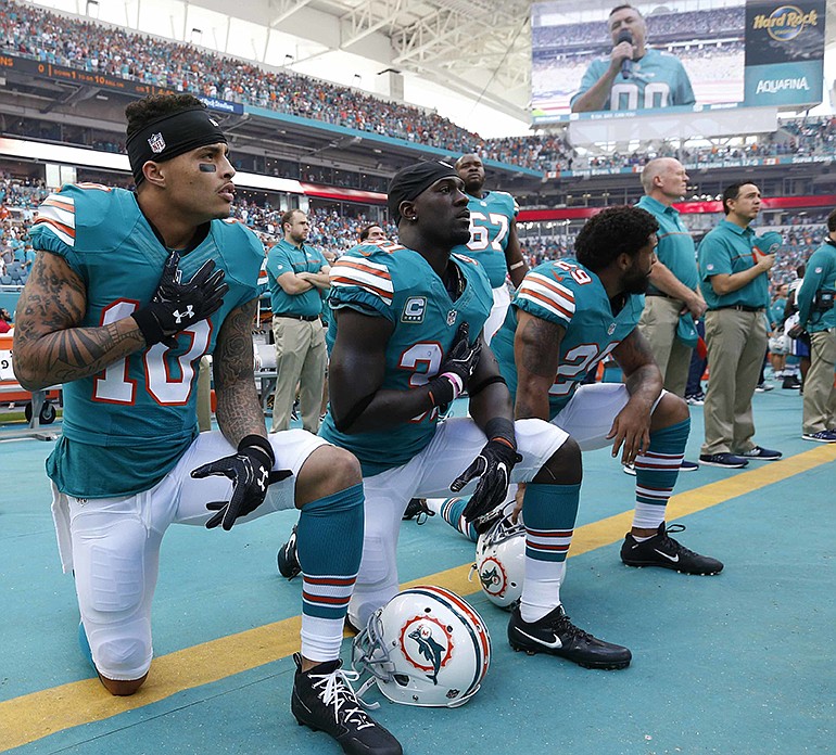 FILE - In this Sunday, Oct. 23, 2016, file photo, Miami Dolphins wide receiver Kenny Stills (10), free safety Michael Thomas (31) and defensive back Chris Culliver (29) kneel during the National Anthem before the first half of an NFL football game against the Buffalo Bills in Miami Gardens, Fla.