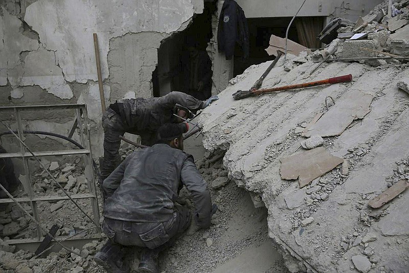 In this photo released on Wednesday Feb. 21, 2018 which provided by the Syrian Civil Defense group known as the White Helmets, shows a member of the Syrian Civil Defense group, searches for victims under the rubble of a destroyed house that attacked by Syrian government forces airstrike, in Ghouta, a suburb of Damascus, Syria.