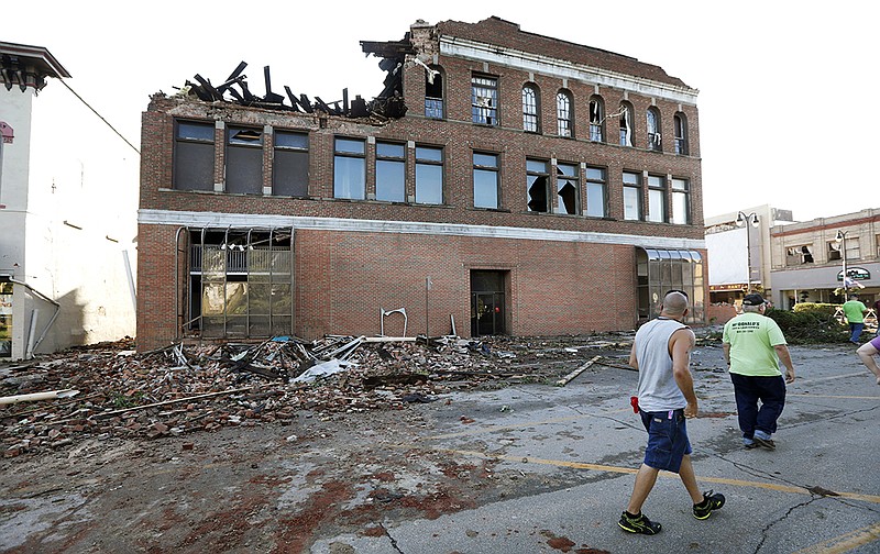 Local residents walk past a tornado-damaged building on Main Street, Thursday, July 19, 2018, in Marshalltown, Iowa. Several buildings were damaged by a tornado in the main business district in town including the historic courthouse. (AP Photo/Charlie Neibergall)