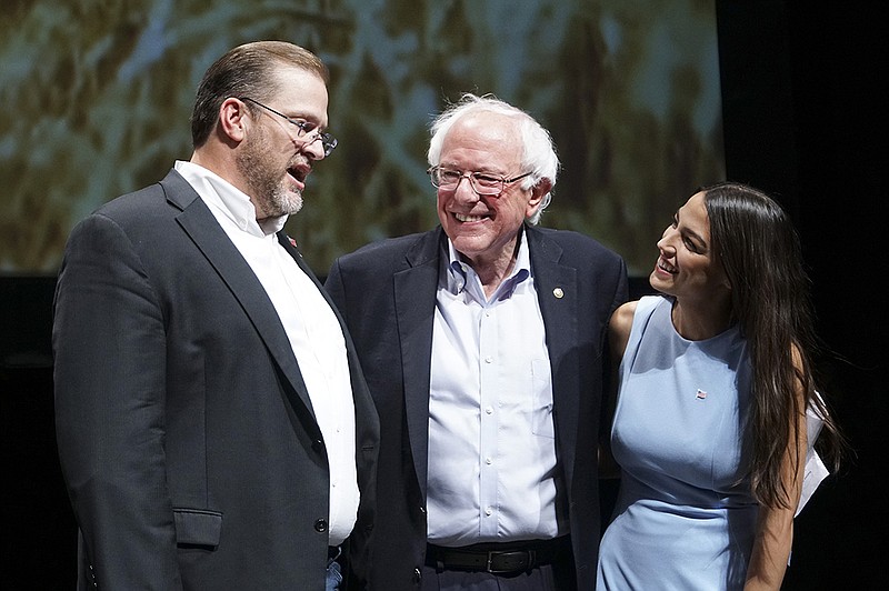 Kansas congressional candidate James Thompson, left, U.S Sen. Bernie Sanders, I-Vt., and Alexandria Ocasio-Cortez, a Democratic congressional candidate from New York, stand together on stage after a rally, Friday, July 20, 2018, in Wichita, Kan. (Jaime Green/The Wichita Eagle via AP)