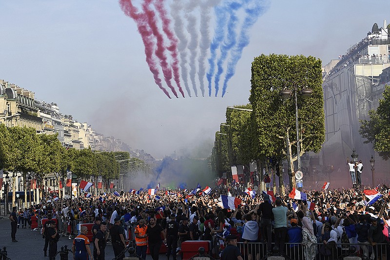 Smoke in the colors of the national flag is released by the French aerobatic squad on the Champs-Elysee avenue in Paris, Monday, July 16, 2018.