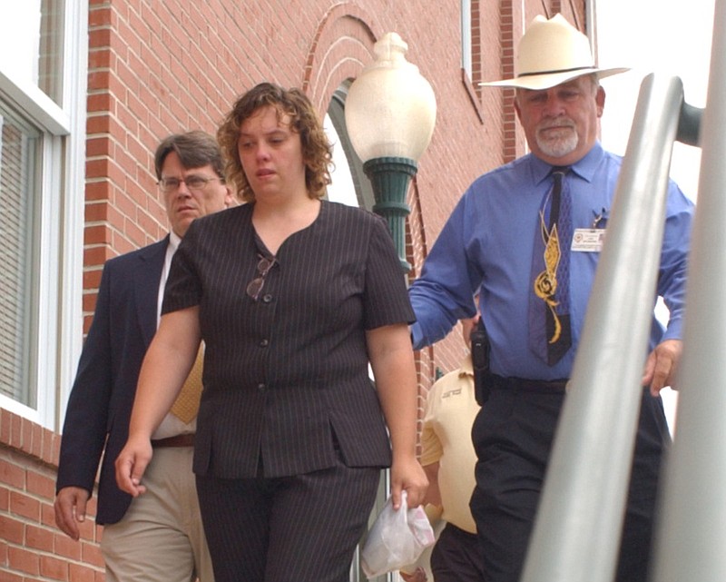 In this 2004 staff file photo, Bledsoe County Sheriff Bob Swafford, right, escorts Michelle Martin from the Bledsoe County Courthouse after she pleaded guilty to second-degree murder in the slaying of her father on Halloween, 2001. Chief Deputy William Angel, left, walks with them to the transport car.