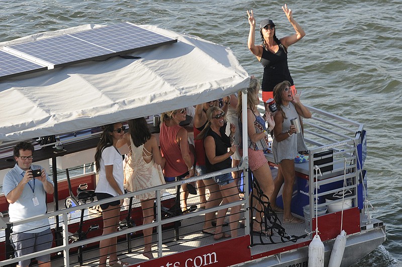 Staff photo by Tim Barber /
A group of young ladies pass behind the Coca-Cola Stage aboard the Chattanooga Cycleboats vessel as Salt N Pepa take the stage. 