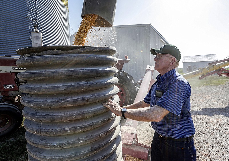 In this July 12, 2018 photo, farmer Don Bloss checks on the operation of an auger transferring corn on his farm in Pawnee City, Neb. Farmers and agricultural economists are worried that president Donald Trump's trade, immigration and biofuels policies will cost farms billions of dollars in lost income and force some out of business. Bloss, who grows corn, soybeans, sorghum and wheat on his farm in the southeastern Nebraska community of Pawnee City, said he's already seen a few neighbors quit farming as they struggled to make a profit even before the tariff battle began this year. (AP Photo/Nati Harnik)