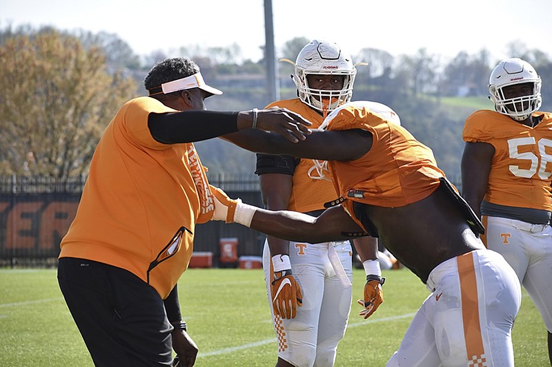 University of Tennessee defensive line coach Tracy Rocker works with Jonathan Kongbo to demonstrate a drill as Kyle Phillips, center, watches.


