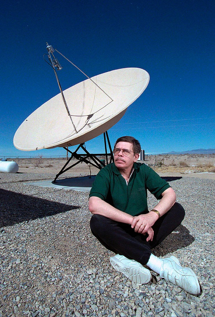 FILE - In this March 7, 1997, file photo, late night talk show host Art Bell sits near a satellite dish at his home in Pahrump, Nev.