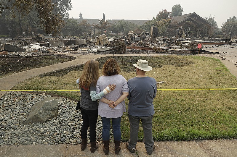 Tim Smith, at right, gets a first look at his wildfire-ravaged home alongside his daughter, Suzie Scatena, center, and aid worker Deborah Coombs Thursday, Aug. 2, 2018, in Redding, Calif. (AP Photo/Marcio Jose Sanchez)