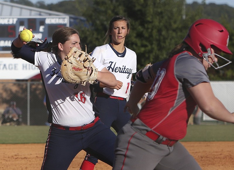 Heritage first baseman Katie Proctor throws to first base while backed up by pitcher Rachel Gibson during a state playoff game against visiting Madison County last season.