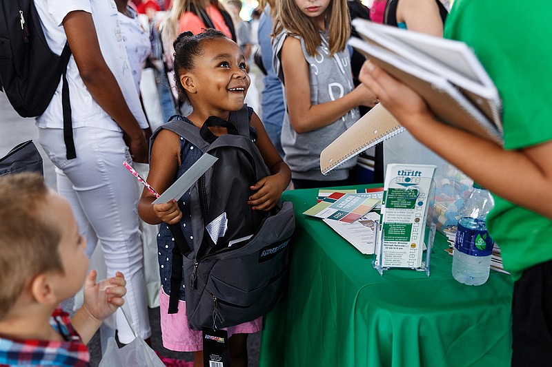 Avah Wilganoski gets a folder from a booth during Hamilton County Schools' Parent University kickoff event at the First Tennessee Pavilion on Saturday, Aug. 4, 2018, in Chattanooga, Tenn. School begins August 8.