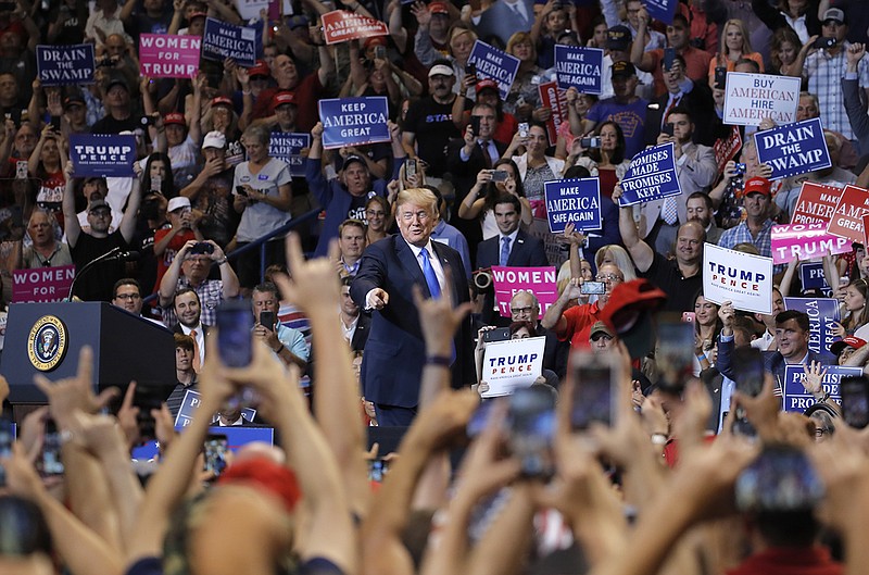 T-shirts and poster signs supportive of the blogger "Q" and the QAnon movement have been showing up at rallies featuring President Donald Trump. (AP Photo/Carolyn Kaster)