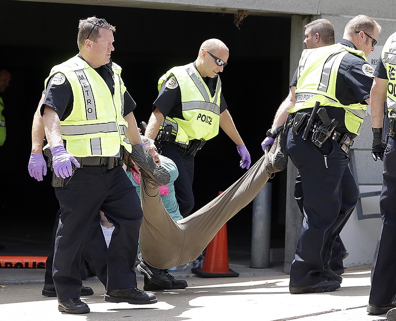 Police remove a demonstrator from outside the headquarters of CoreCivic, Monday, Aug. 6, 2018, in Nashville, Tenn.