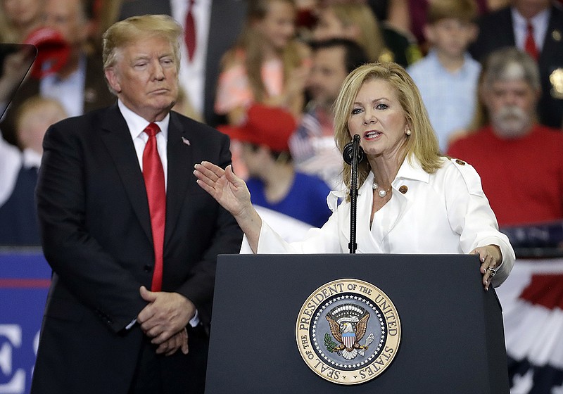 In this May 29, 2018 file photo, President Donald Trump listens as Rep. Marsha Blackburn, R-Tenn., speaks at a rally at the Nashville Municipal Auditorium in Nashville, Tenn. Blackburn is supposed to do well among Tennessee's hog farmers and whiskey makers. Yet the Republican Senate candidate is struggling to explain President Donald Trump's nascent trade war to her state's local business community. (AP Photo/Mark Humphrey)