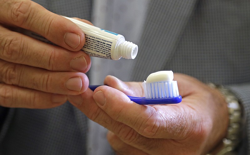 In this photo taken Friday, Aug. 3, 2018, Philippe Hujoel, a dentist and University of Washington professor, holds a toothbrush and toothpaste in an office at the school in Seattle. Dental health experts worry that more people are using toothpaste that skips the most important ingredient - the fluoride - and leaves them at a greater risk of cavities. (AP Photo/Elaine Thompson)