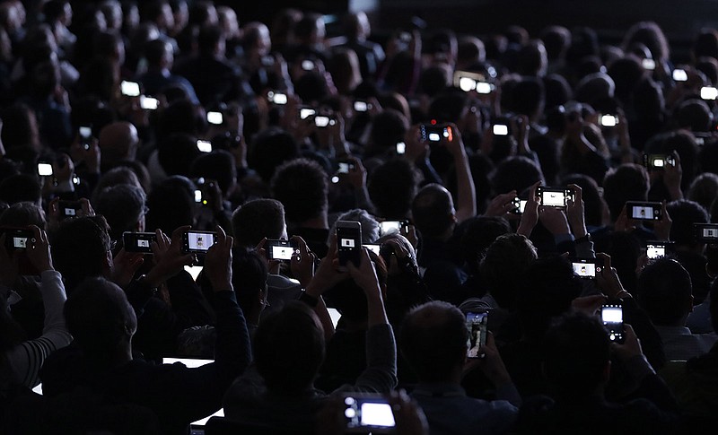 In this March 27, 2018, photo, people record the reveal of the new iPad during an Apple event at Lane Technical College Prep High School in Chicago. The Trump administration's hit list of Chinese products facing import taxes includes key components used in gadgets that can be wirelessly operated through a smartphone or another device. The tariffs also will nail networking equipment that makes the internet work. Trump has also threatened to impose tariffs on a total of $500 billion worth of Chinese items. That could affect major technology products such as Apple's iPhones, which are assembled in China. (AP Photo/Charles Rex Arbogast, File)