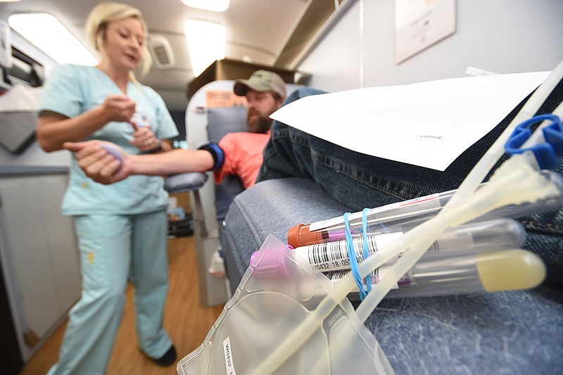 Blood tubes await as phlebotomist Hannah Wooten, left, works to get a blood donation from Alan Paup late Wednesday afternoon inside one of two Blood Assurance buses on the lot at Piney Grove Baptist Church in Trenton. / Staff photo by Tim Barber
