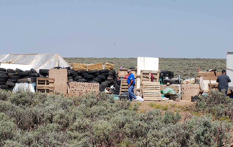Taos County Solid Waste Department Director Edward Martinez, center, surveys property conditions at a disheveled living compound at Amalia, N.M., on Tuesday, Aug. 7, 2018. A New Mexico sheriff said searchers have found the remains of a boy at the makeshift compound that was raided in search of a missing Georgia child. (AP Photo/Morgan Lee)